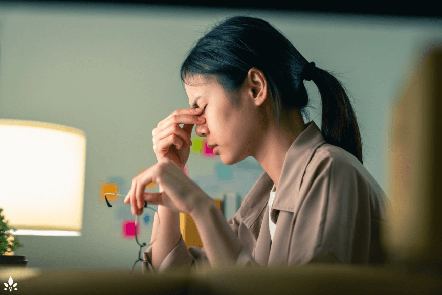 Woman with migraine and other health challenges sitting at her desk and working.