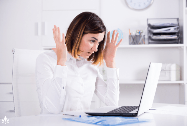 A woman sitting at a desk with her hands up, addressing women’s health challenges at work.