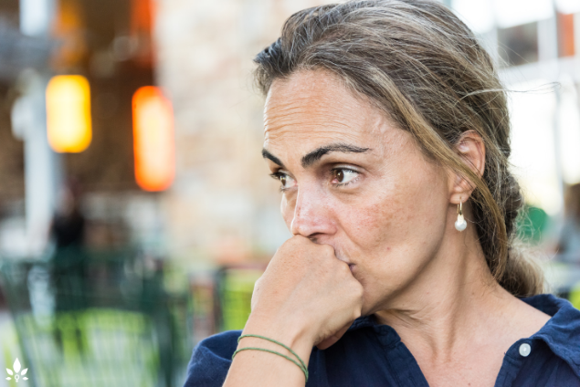 A woman looks pensively to the side, with a worried expression on her face, symbolizing health concerns for female employees in UAE