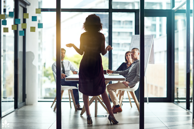 A woman presenting in an office with a group of people. Discover Stress Management In UAE businesses